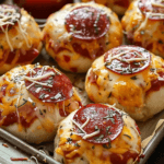 Cheesy Pepperoni Pizza Bombs topped with melted cheese, pepperoni slices, and herbs on a baking sheet.