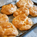 Freshly baked golden-brown cloud bread pieces on a baking sheet lined with parchment paper.