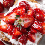 Roasted strawberry whipped ricotta toast topped with vibrant, glossy strawberries on a slice of crusty bread.