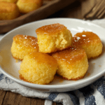 Southern-style honey butter cornbread poppers stacked on a white plate, drizzled with golden honey for a sweet and savory treat.