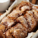 A freshly baked loaf of Dollywood cinnamon bread, drizzled with a sweet glaze, showcasing its golden-brown, soft, and fluffy texture.