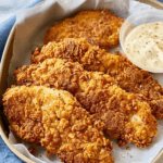 Crispy, golden air-fried chicken cutlets with a crunchy coating, served with a side of creamy Caesar dressing for dipping.