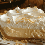 A luscious slice of Amish peanut butter cream pie with a rich, creamy filling, topped with fluffy whipped cream and sprinkled with crushed peanuts.