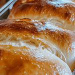 Freshly baked loaves of Amish White Bread with a golden, glossy crust and soft, airy texture.