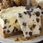 A slice of no-bake chocolate chip cookie dough cheesecake with a graham cracker crust, studded with chocolate chips.