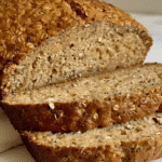 Close-up of sliced flourless oat and chia seed bread with a golden crust and a hearty, textured crumb.